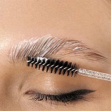 Close-up of a woman with freshly microbladed eyebrows, wearing a pink face mask, highlighting the detailed brow work.