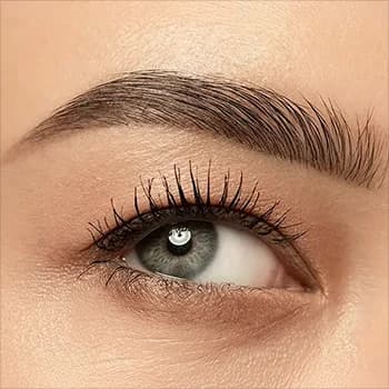 Close-up of a woman with freshly microbladed eyebrows, highlighting defined brows, full lashes, and glossy lips.